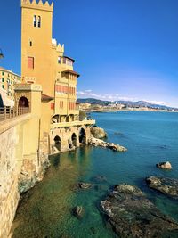 Buildings by sea against blue sky