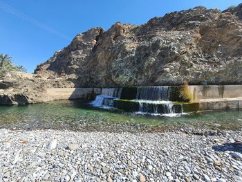 Scenic view of rocks by river against sky