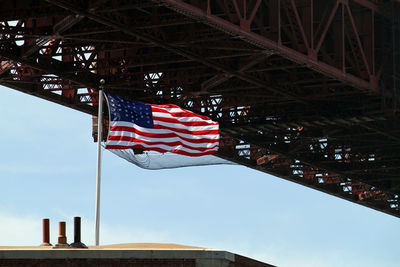 American flag waving in the wind next to the golden gate bridge in san francisco, california
