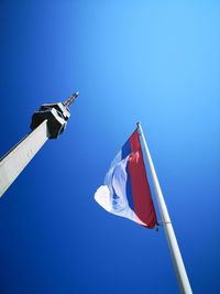 Low angle view of flag against clear blue sky