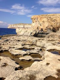 Rock formations on beach against sky