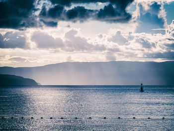 Quiet adriatic sea between islands with buoy and sun rays breaking through clouds