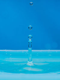 Close-up of drop falling on blue surface