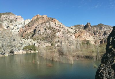 Scenic view of river and mountains against clear blue sky