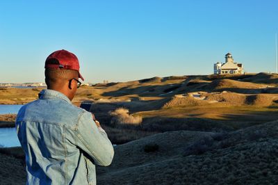 Side view of man standing on landscape against clear sky