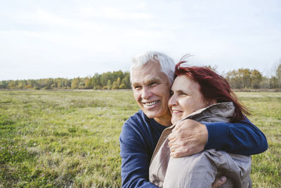 Happy senior couple embracing while looking away on field