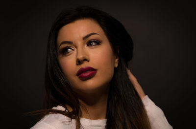 Close-up portrait of beautiful young woman over black background