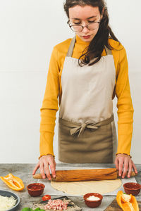 Caucasian teenage girl in an apron prepares pizza.