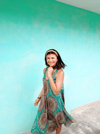 Portrait of smiling young woman standing against blue wall