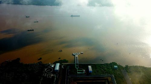 High angle view of birds flying over lake against sky