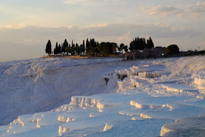 Scenic view of snow covered field against sky during sunset