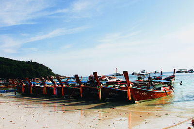 Gondolas moored at sea shore against sky