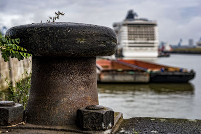 Close-up of metal hook in harbor against sky