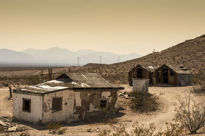 Abandoned houses in ghost town against clear sky during sunset