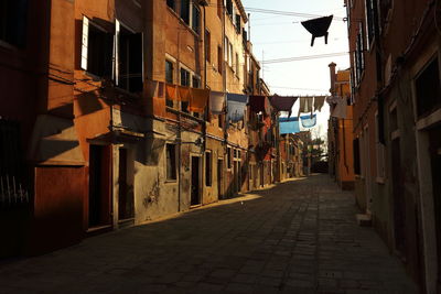 Clothes drying over narrow street amidst buildings in city