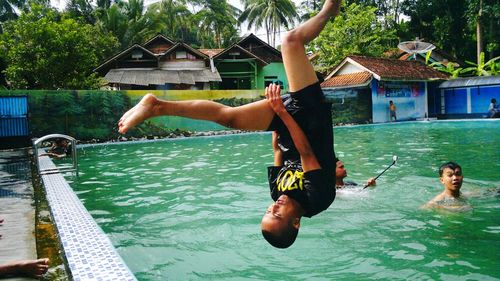 Full length of shirtless man jumping in swimming pool