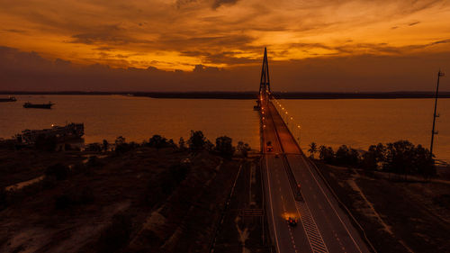 High angle view of city by sea against sky during sunset