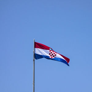 Low angle view of flag against clear blue sky