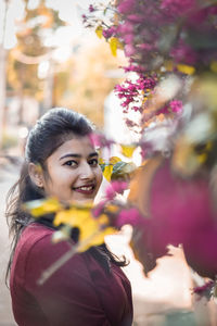 Portrait of smiling woman by flowering plants