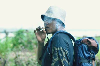 Man smoking cigarette against sky