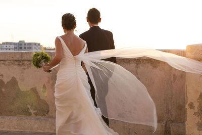 Rear view of newlywed couple against sky