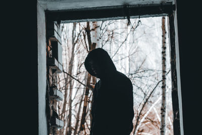Side view of silhouette man standing by window