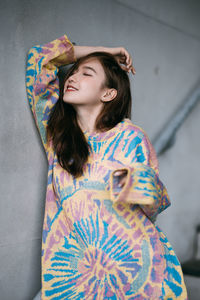 Portrait of young woman standing against wall