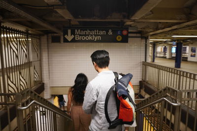 Rear view of man and woman standing on railing