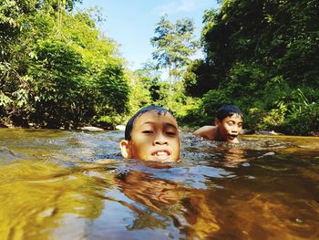 Boys swimming in river at forest