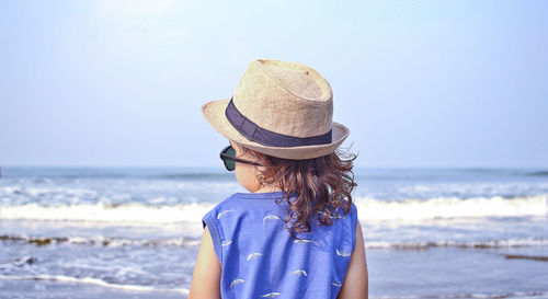 Boy wearing hat at beach against clear sky