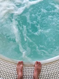 Low section of man relaxing on poolside