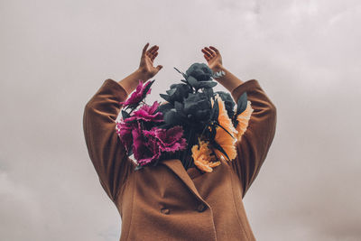 Low section of woman standing by pink flowering against sky