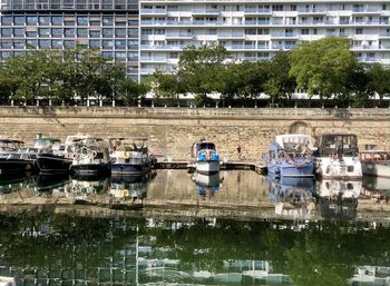 Boats moored in lake against buildings in city