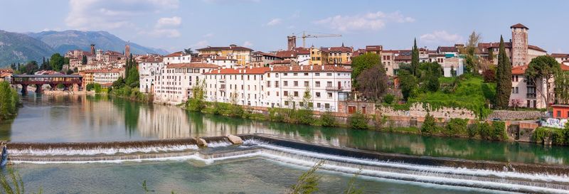 Panoramic shot of river by buildings in town against sky