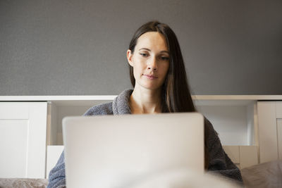 Close-up of young woman or girl sitting on bed, working on laptop,using computer and video chat