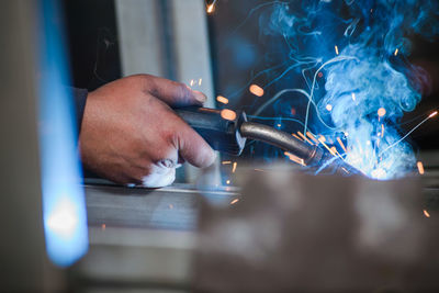 Cropped hand of man welding metal at workshop