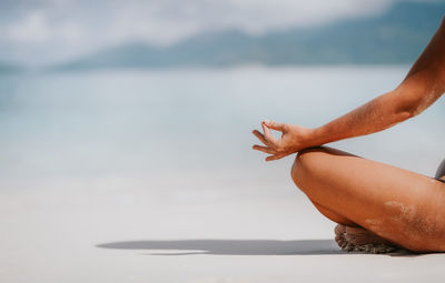 Midsection of man sitting on shore at beach