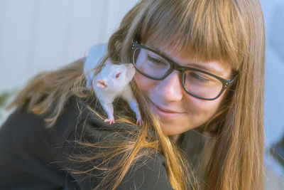 Teenage girl in glasses plays with white pet rat