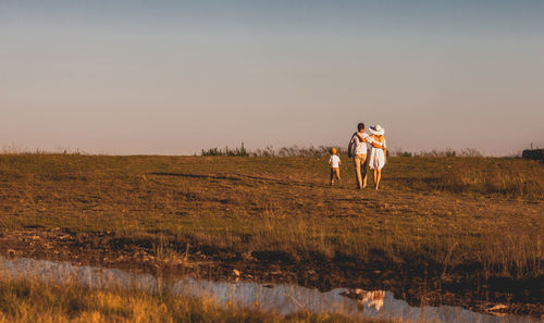 People standing on field against sky during sunset