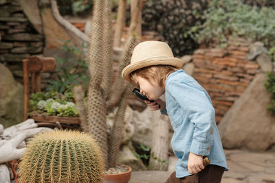 Preschooler boy inspecting desert cactus using magnifying glass. in the desert