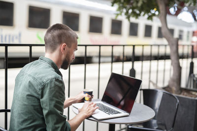 Man using laptop in outdoor cafe