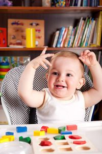 Cute baby boy playing with toy blocks on table