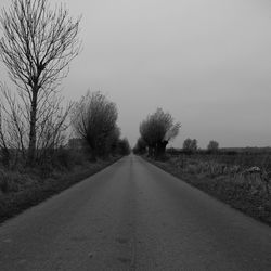 Road amidst trees against clear sky