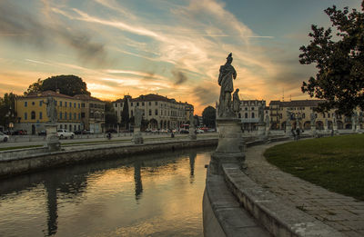 Panoramic view of canal and buildings against sky during sunset