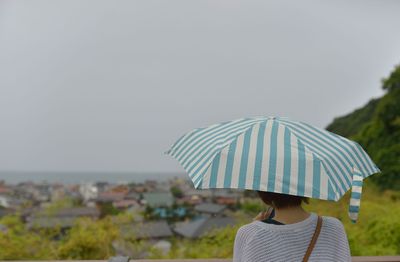 Rear view of woman holding umbrella at beach