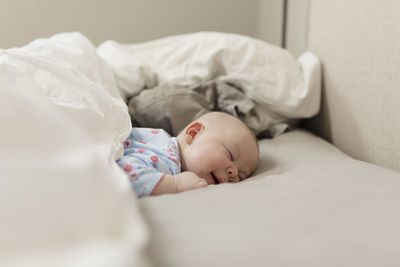 Cute baby girl sleeping on bed at home