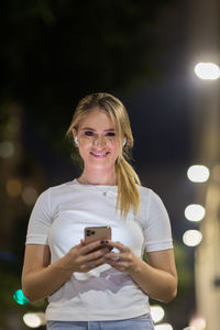 Woman using a smartphone at night time on the street. mobile phone, technology, urban .