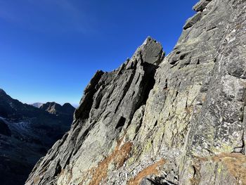 Low angle view of rocky mountains against clear blue sky