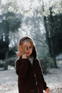 Portrait of boy with leaf standing on field during autumn