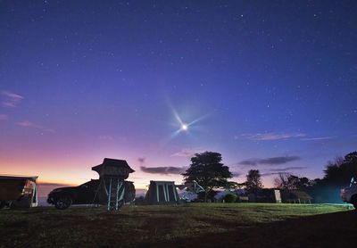 Rear view of man standing on field against sky at night